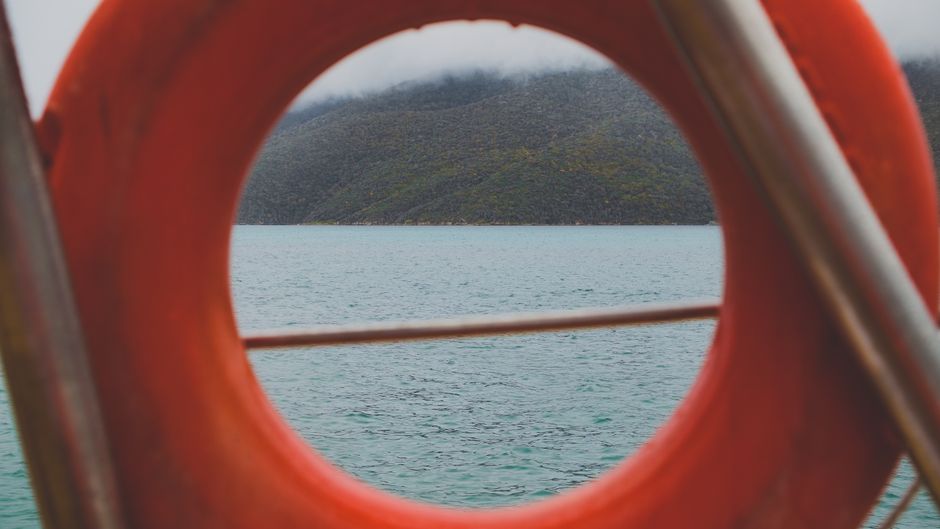 A tranquil scene of a mountain lake framed by a life buoy, offering a sense of safety and adventure.